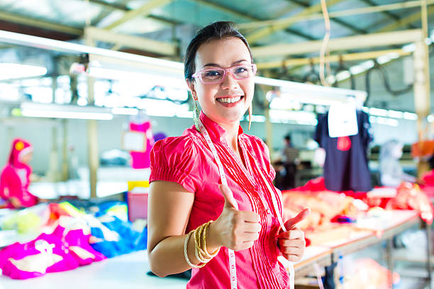 Female Chinese asian dressmaker or designer standing proudly in a textile factory, it is her workplace